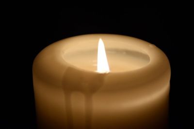 Close-up of illuminated candle over black background