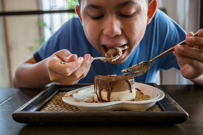 Boy eating cake while sitting at cafe