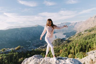 Beautiful woman walking on rock against sky