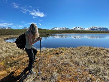 Rear view of woman standing in lake against sky