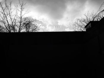 Low angle view of bare tree against cloudy sky