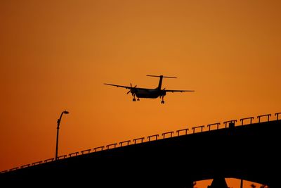 Low angle view of silhouette airplane against clear sky during sunset