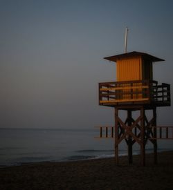 Lifeguard hut on beach against sky during sunset