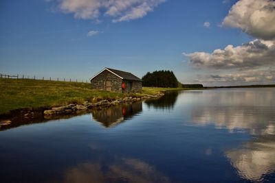 Scenic view of lake by building against sky