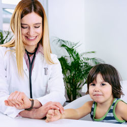 Female doctor checking girl wrist in hospital