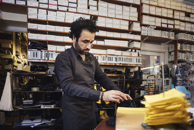 Man wearing apron while looking at shoes in store