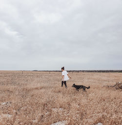 Woman walking with dog on field