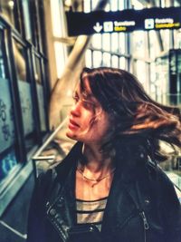 Portrait of young woman looking through window