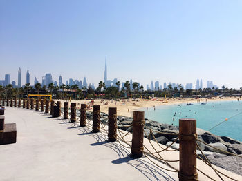 Wooden posts in sea against buildings in city in dubai, uae