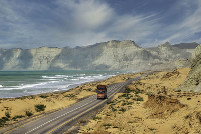 Scenic view of road by sea against sky