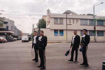 Full length portrait of friends standing on road in city