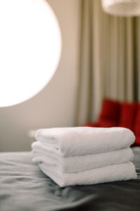 Stack of towels on bed against window in hotel