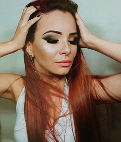 Close-up of beautiful woman with hand in hair against wall at home