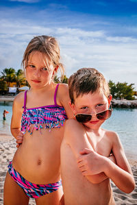 Cute siblings standing on beach