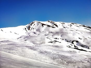 Scenic view of snowcapped mountains against clear blue sky