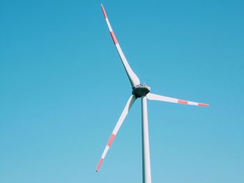 Low angle view of wind turbine against blue sky
