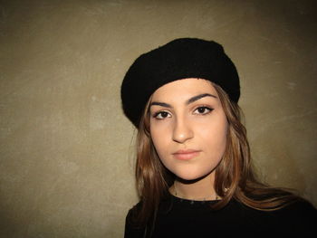 Portrait of beautiful young woman against wall