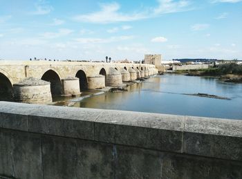 Bridge over river against cloudy sky