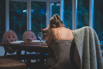 Rear view of woman sitting on table at restaurant