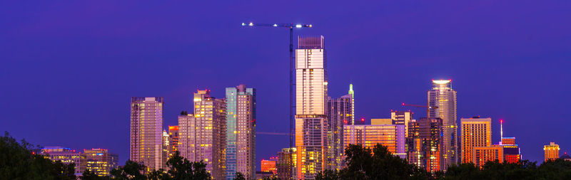 Illuminated buildings in city against sky at night