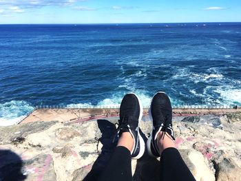 Low section of woman by sea against sky