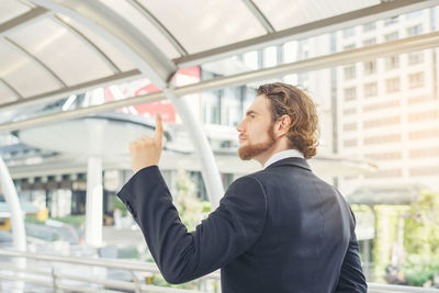 Young businessman gesturing while standing on elevated walkway 