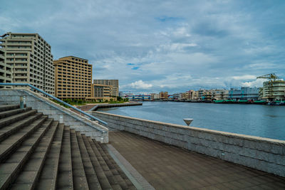 Buildings by river against sky in city