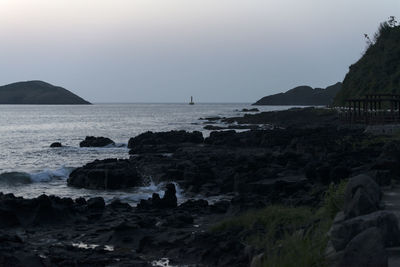 Scenic view of sea and rocks against clear sky