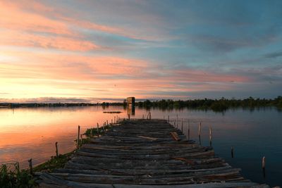 Pier over lake against sky during sunset