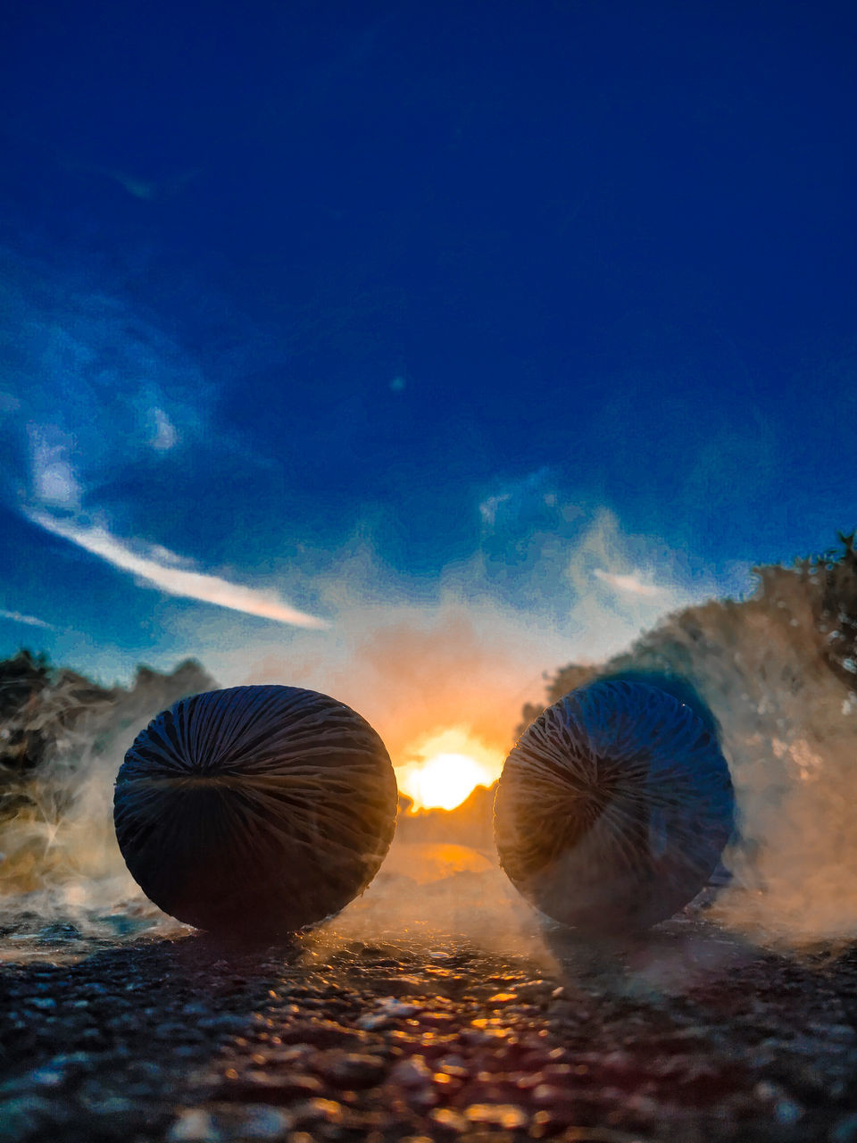 CLOSE-UP OF ROCKS ON FIELD AGAINST SUNSET SKY