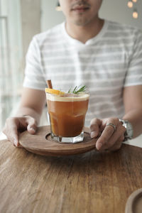 Midsection of man holding drink on table