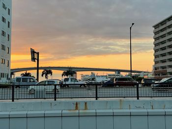 Bridge by buildings against sky during sunset