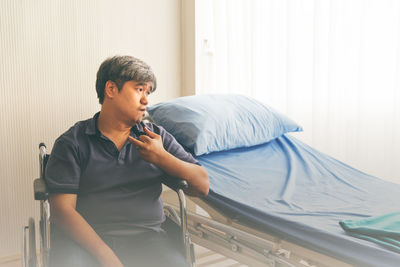 Man looking at camera while sitting on bed