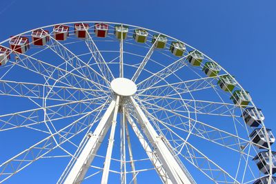 Low angle view of ferris wheel against clear blue sky