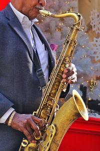 Midsection of senior male musician playing saxophone outdoors