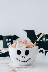 Painted white cup scary jacks face with marshmallows hot chocolate cacao drink diy for kids. 