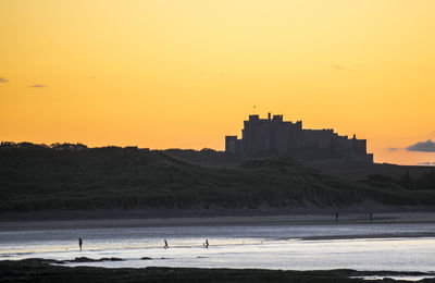 Silhouette of buildings on beach at sunset