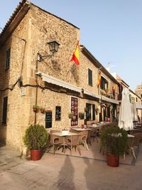 Potted plants on table by building against clear sky