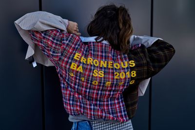 Rear view of woman with arms raised standing against wall