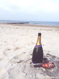 Close-up of bottle on beach against sky