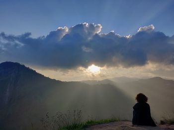 Rear view of man standing on mountain against sky