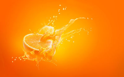 Close-up of water splashing against orange background