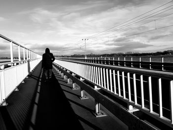 Rear view of man walking on footbridge