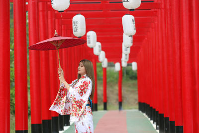 Side view of woman holding umbrella standing outdoors