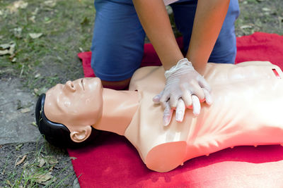 Low section of woman practicing cpr on dummy at field