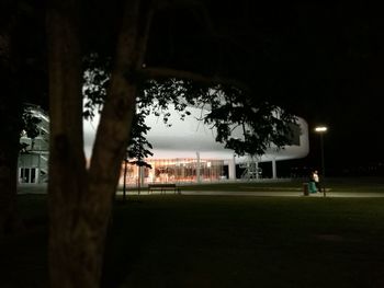 People playing soccer on field against sky at night