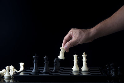 Midsection of man playing guitar against black background