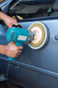 Cropped hands of man polishing car in auto repair shop