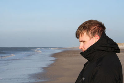 Side view of man at beach against sky