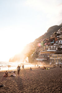 People on beach against sky in city